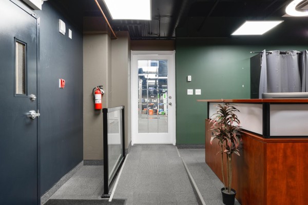 Hallway with dark grey walls, a fire extinguisher, and a glass door leading to another room. - 401, 10154 104 St Nw, Edmonton
