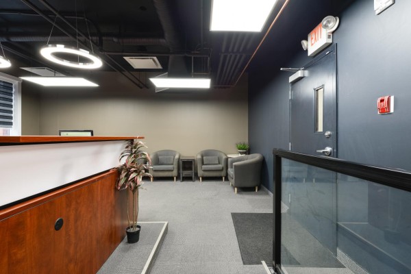 View of the reception area from the side, showing chairs, desk, and an exit door. - 401, 10154 104 St Nw, Edmonton
