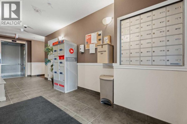 Apartment building lobby with mailboxes, parcel lockers, and an elevator. - 401, 174 N Railway Street, Okotoks