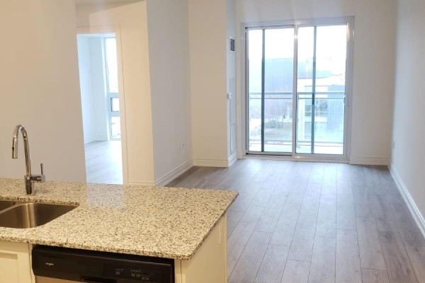 View from kitchen island showing a living area with large sliding glass doors and balcony access. - 401 - 1050 Main Street, Milton