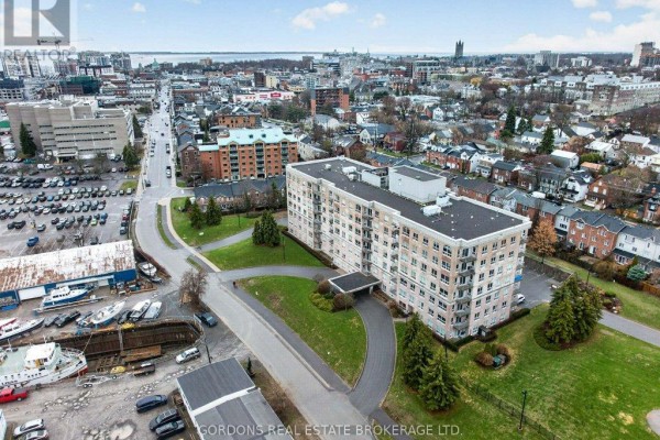 Aerial view showing the apartment building, surrounding grounds, and a distant cityscape. - 401 - 350 Wellington Street, Kingston