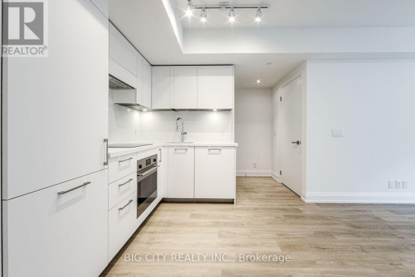 Modern white kitchen with stainless steel appliances, quartz countertops, and subway tile backsplash. - 401 - 36 Brentcliffe Road, Toronto