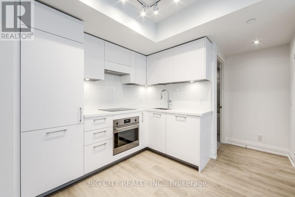 Corner view of the white modern kitchen with integrated appliances and ample cabinet storage. - 401 - 36 Brentcliffe Road, Toronto