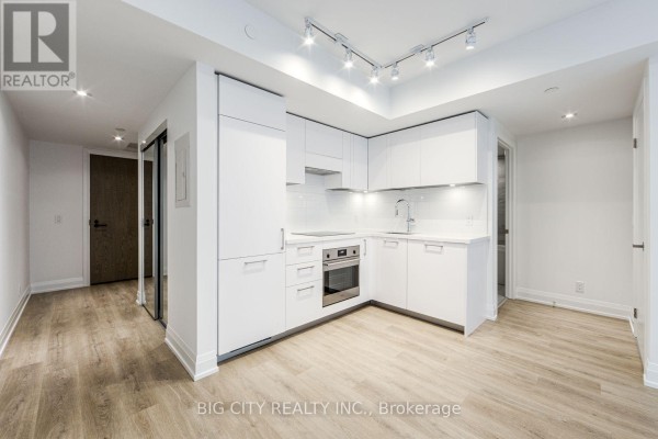 View of the open living space and modern white kitchen from the hallway entrance. - 401 - 36 Brentcliffe Road, Toronto