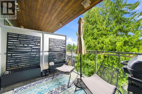 Covered balcony with chairs, a table, a grill, and views of green trees and a blue sky. - 401 1327 Draycott Road, North Vancouver