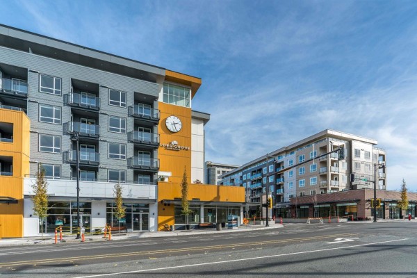 Street-level view of the apartment building with shops on the ground floor. - 401 27215 Aldergrove Town Centre Drive, Langley