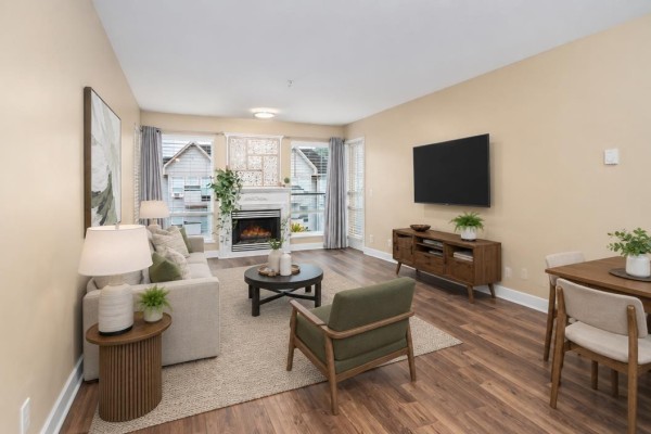 Living room with fireplace, beige sofa, armchair, coffee table, and TV on a console. - 401 33738 King Road Road, Abbotsford