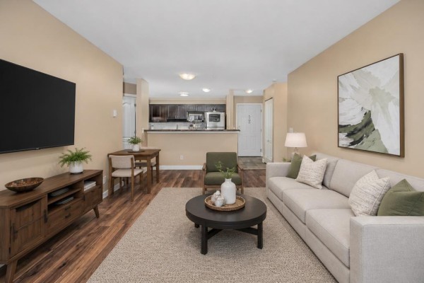 Living room showing sofa, fireplace, and entrance to the kitchen area with dark cabinets. - 401 33738 King Road Road, Abbotsford