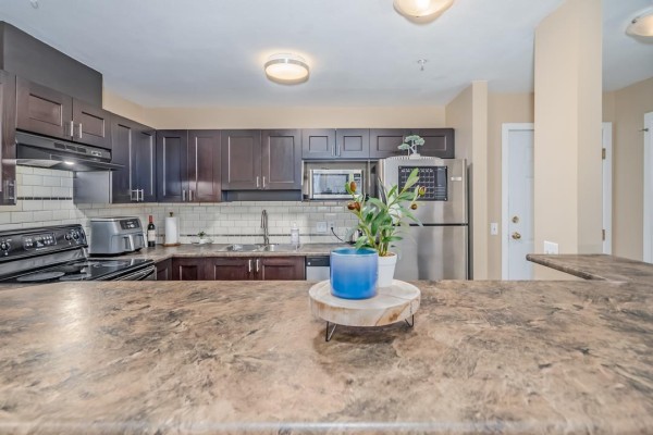 Kitchen with dark wood cabinets, stainless steel appliances, and granite-style countertops. - 401 33738 King Road Road, Abbotsford