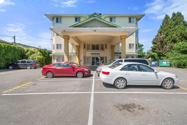 Side view of apartment building exterior with parking lot and trees. - 401 46777 Yale Road, Chilliwack Proper East, Chilliwack