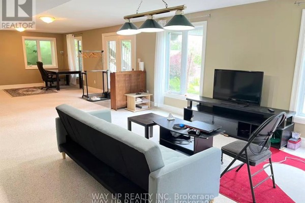 Living room with a sofa, coffee table, TV stand, and large windows. - 401 Kingbird Court, London North