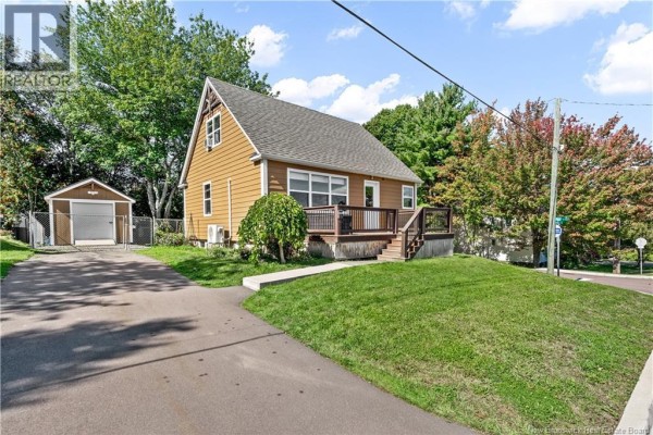 Exterior view of a light brown bungalow with a detached garage and asphalt driveway. - 401 Montgomery Avenue, Riverview