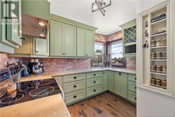 Kitchen with light green cabinets, double sink, brick tile backsplash, and spice rack. - 401 Montgomery Avenue, Riverview