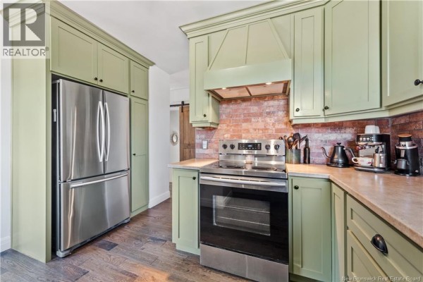 Kitchen with light green cabinets, stainless steel French door refrigerator, and brick backsplash. - 401 Montgomery Avenue, Riverview