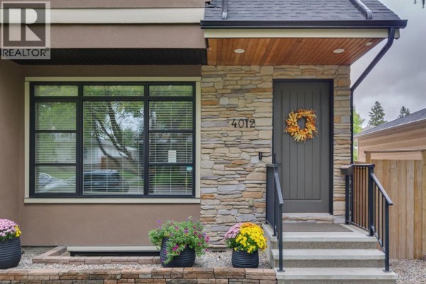 Close-up of the front entrance of a duplex with a stone facade, wooden soffit, and dark gray door. - 4012 2 Street Nw, Calgary