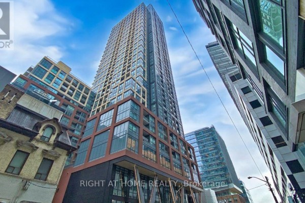 Exterior view of a tall condominium building with glass balconies and surrounding city structures. - 4013 - 108 Peter Street, Toronto