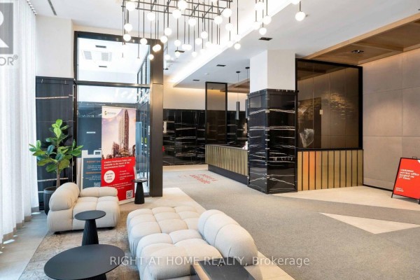 Hotel-style lobby with light grey carpet, beige sofas, black side tables, and marble accents. - 4013 - 108 Peter Street, Toronto