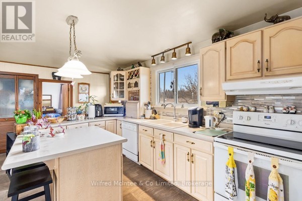 Kitchen with island seating, white cabinets, and tiled backsplash - 401395 Grey Rd 4 West Grey