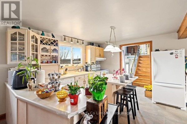 Kitchen with white cabinets, island, and view of wood stairs - 401395 Grey Rd 4 West Grey