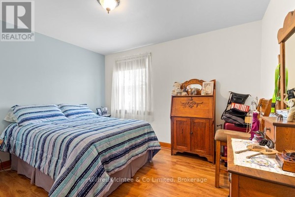 Bedroom with double bed, striped comforter, wooden secretary desk, and dresser - 401395 Grey Rd 4 West Grey