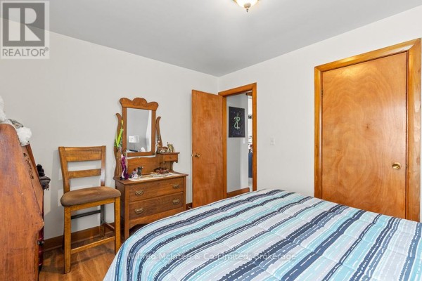 Bedroom with wooden dresser, mirror, and striped bedding - 401395 Grey Rd 4 West Grey