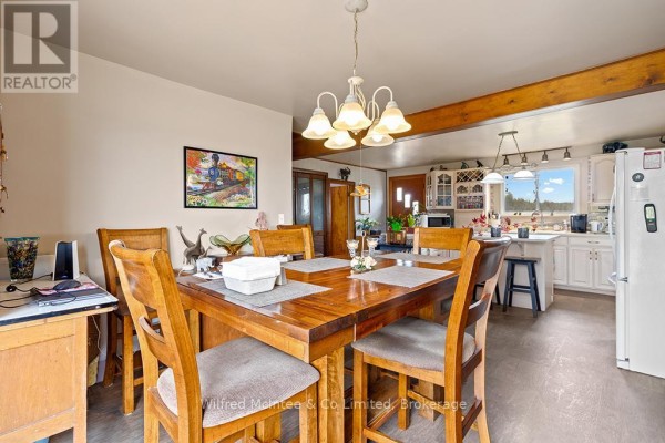 Wooden dining table with chairs, open to kitchen with white cabinets and island - 401395 Grey Rd 4 West Grey