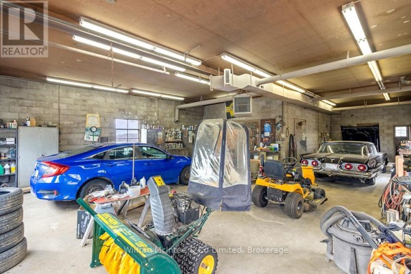 Garage with blue sedan, vintage black car, lawn tractor, snowblower - 401395 Grey Rd 4 West Grey