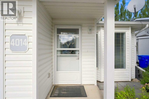 Side exterior view of the white duplex, showing the attached garage and walkway. - 4014 Shannon Drive, Olds