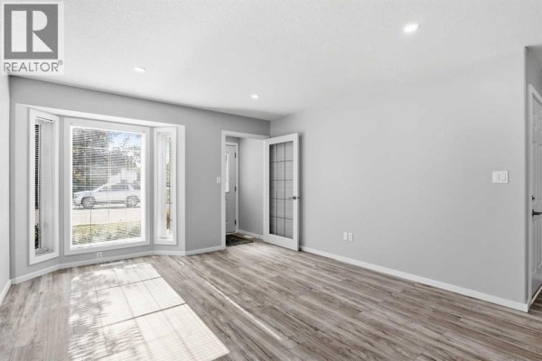Interior entryway of the duplex, featuring a white door, wood bench, and coat hooks. - 4014 Shannon Drive, Olds