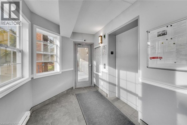 Apartment building hallway with elevator, gray tile floor, and two windows. - 4015 Kilmer Drive Unit# 204, Burlington