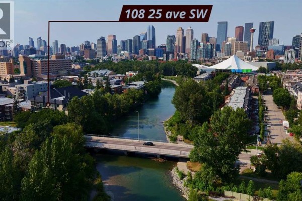 Exterior of a brick apartment building surrounded by trees, with Calgary skyline in the distance. - 402, 108 25 Avenue Sw, Calgary