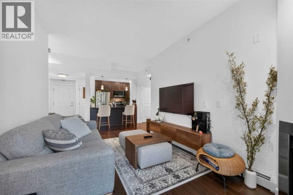 Bathroom with a white toilet, bathtub, sink, and patterned tile wall. - 402, 108 25 Avenue Sw, Calgary