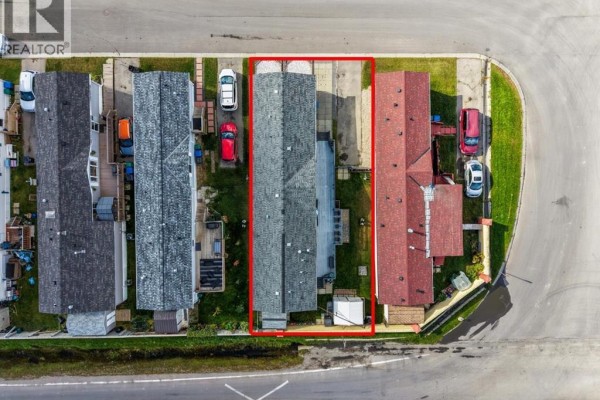 Aerial view of a row of mobile homes, with the property outlined in red. - 402, 1101 84 Street Ne, Calgary