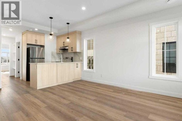 Open concept living area and kitchen with light wood cabinets, stainless steel appliances, and white walls. - 402, 156 Park Street, Cochrane