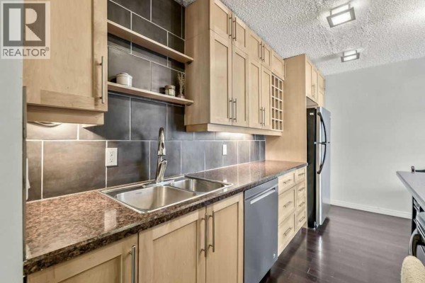 Kitchen view with light wood cabinets, granite countertops, and dark tile backsplash. - 402, 2140 17a Street Sw, Calgary