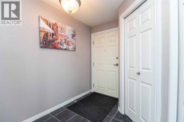 Apartment entrance with grey walls, a white door, and a framed picture. - 402, 69 Ironstone Drive, Red Deer