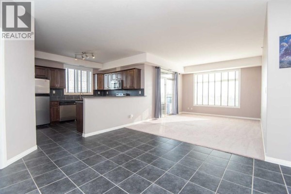 Open concept living and kitchen area with dark tiled floors and large windows. - 402, 69 Ironstone Drive, Red Deer