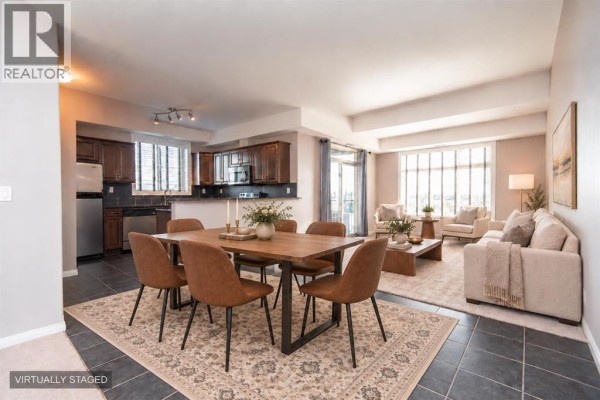 Staged dining and living area with a wooden table and plush sofa. - 402, 69 Ironstone Drive, Red Deer