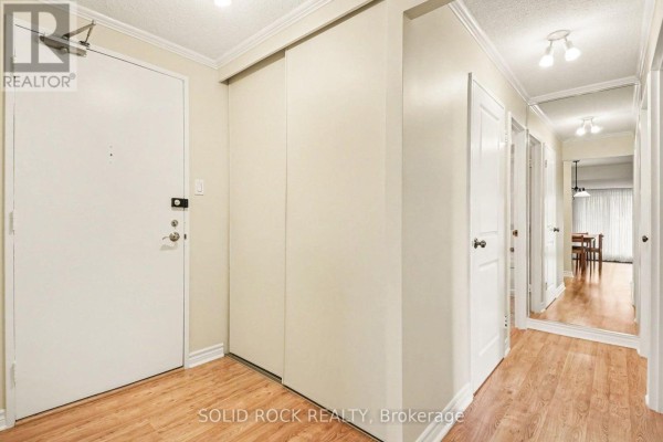 Apartment entryway with light wood floors, a white door, and a large mirrored closet. - 402 - 1171 Ambleside Drive, Ottawa