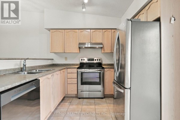 Kitchen with light wood cabinets, stainless steel appliances, and composite countertops and sink. - 402 - 1470 Bishops Gate, Oakville