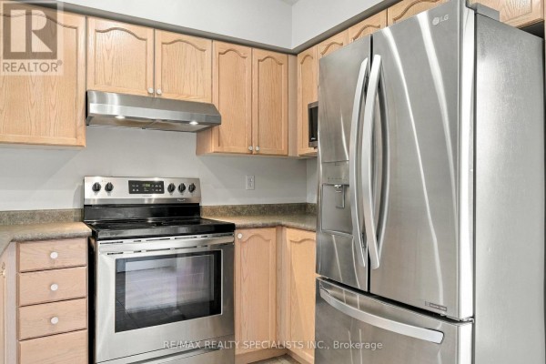 Kitchen showing light wood cabinets, stainless steel stove, and large stainless steel refrigerator. - 402 - 1470 Bishops Gate, Oakville