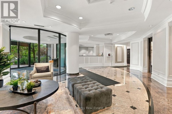 Building lobby with marble floors, a circular seating area, and reception desk. - 402 - 16 Dallimore Circle, Toronto