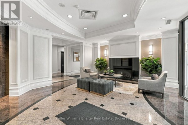 Building lobby with plush seating, fireplace, and decorative wall paneling. - 402 - 16 Dallimore Circle, Toronto