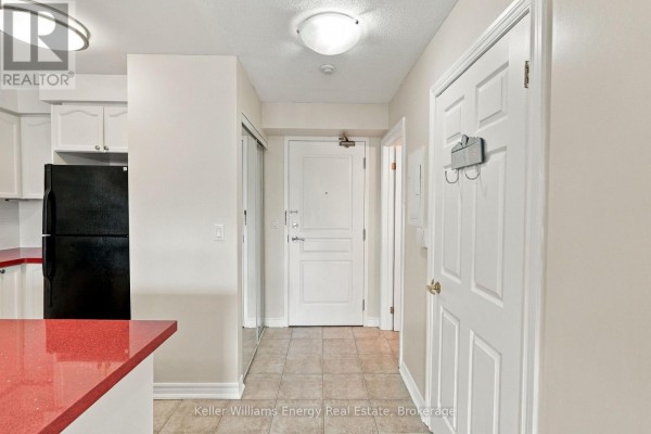 Apartment entrance hallway with tiled floors, a white door, and mirrored closet. - 402 - 16 Dallimore Circle, Toronto