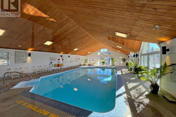 Indoor swimming pool with a wood-paneled ceiling and large windows. - 402 - 24 Ramblings Way, Collingwood
