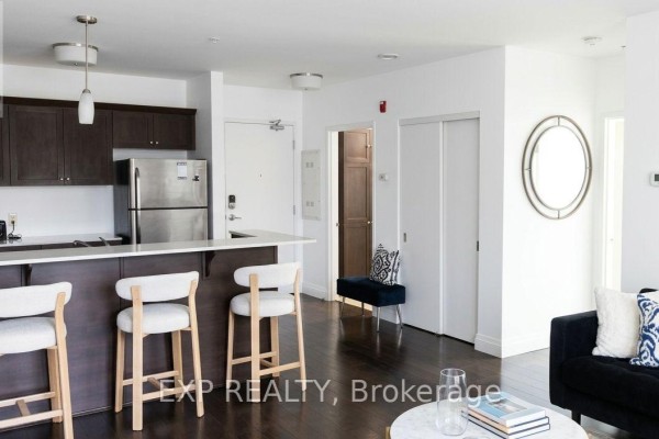Interior hallway showing a stainless steel refrigerator, dark wood cabinets, and a front door. - 402 - 26 Wellington Street, St  Catharines