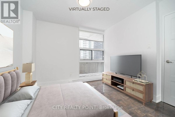 Bedroom with a bed, TV, and a large window showing city buildings. - 402 - 33 Isabella Street, Toronto