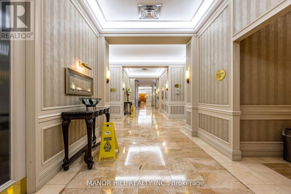 Interior hallway with patterned wallpaper, marble floors, decorative console table, and lighting sconces. - 402 - 35 Kingsbridge Garden Circle, Mississauga