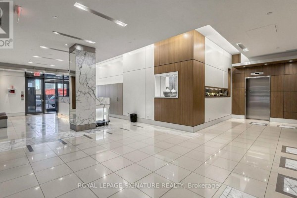 Spacious, modern lobby with white tiled floors, marble pillars, and wood paneling. - 402 - 500 St Clair Avenue W, Toronto