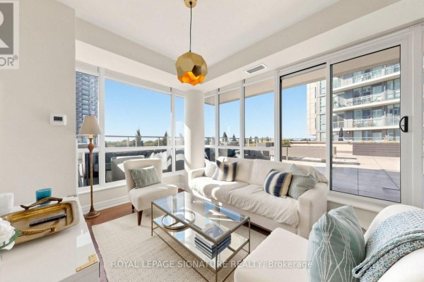 Bright living room with white sofa, armchair, glass coffee table, and large windows. - 402 - 500 St Clair Avenue W, Toronto